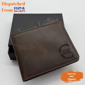 May include: A brown leather wallet with the name "CAGE" embossed on the front. The wallet is rectangular and appears to be new. The wallet is displayed on top of a black box. The text "Dispatched From USA" is visible in the image.