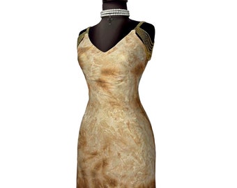 Könnte beinhalten: Ein figurbetontes Kleid mit einem braunen und weißen Batik-Muster. Das Kleid hat goldene Perlenriemen und eine Perlenkette um den Hals.
