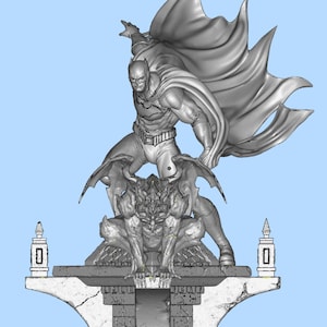 Peut inclure: Statue grise de Batman avec une cape flottante, debout sur une gargouille. La statue est sur une base détaillée en forme de pierre avec des éléments architecturaux. La figurine est dans une pose dynamique.