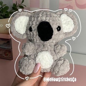 Może przedstawiać: Ręcznie robiony szary szydełkowy miś koala z białymi akcentami na uszach i brzuchu. Koala ma czarne oczy i czarny nos. Obraz zawiera tekst "@MellowstitchesCo".