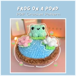 Pode incluir: Um padrão de crochê PDF de um sapo em um lago azul com flores rosa e brancas. O texto "FROG ON A POND PDF Crochet Pattern" está no topo. O sapo é verde claro com olhos pretos. O lago é cercado por uma borda marrom.