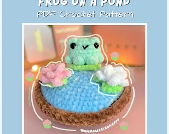 May include: A crocheted frog sits on a blue pond with pink and white flowers. The text "FROG ON A POND PDF Crochet Pattern" is at the top. The frog is light green with black eyes. The pond is surrounded by a brown border.