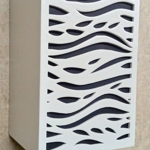 May include: White wooden wall panel with a cut-out design of wavy lines and leaves. The panel is painted white and has a dark grey background.