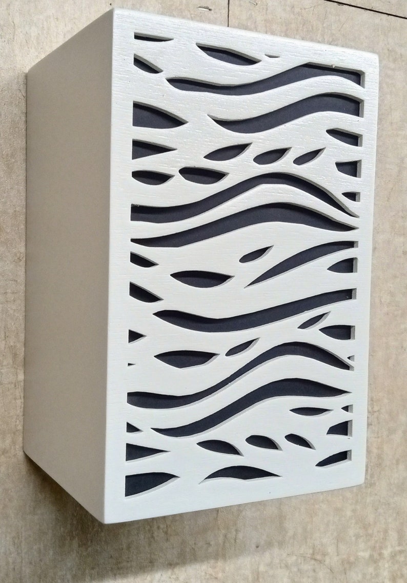 May include: White wooden wall panel with a cut-out design of wavy lines and leaves. The panel is painted white and has a dark grey background.