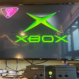 May include: A white ceramic mug with a black handle and the text "But First, Coffee" in a handwritten style. The mug is on a white surface. The mug is approximately 10 cm tall.