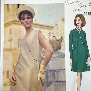Könnte beinhalten: Ein Vintage-Schnittmuster von Vogue Grand Couturier mit zwei Kleiderdesigns für Damen. Das erste Design ist ein beigefarbenes, ärmelloses Kleid mit einer diagonalen Naht und Knöpfen. Das zweite Design ist ein grünes, langärmeliges Kleid mit einer diagonalen Naht und Knöpfen. Der Text auf dem Schnittmuster lautet "Vogue Grand Couturier", "Federico Forquet d'Italie" und "1968".