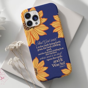 Puede incluir: Funda de tel&eacute;fono azul marino con dise&ntilde;o de girasoles amarillos y naranjas. El texto "And God said...and It Was So!" est&aacute; en blanco. Accesorio protector para smartphone.
