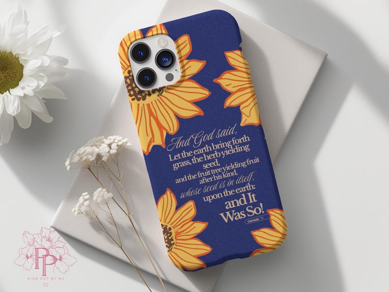 Puede incluir: Funda de tel&eacute;fono azul marino con dise&ntilde;o de girasoles amarillos y naranjas. El texto "And God said...and It Was So!" est&aacute; en blanco. Accesorio protector para smartphone.