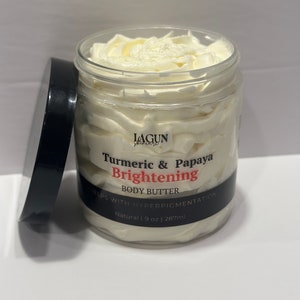Może przedstawiać: Biały słoik z masłem do ciała rozjaśniającym z kurkumą i papają marki LAGUN skincare. Słoik jest oznaczony napisem "Pomaga w hiperpigmentacji" i "Naturalny | 9 oz | 287ml".