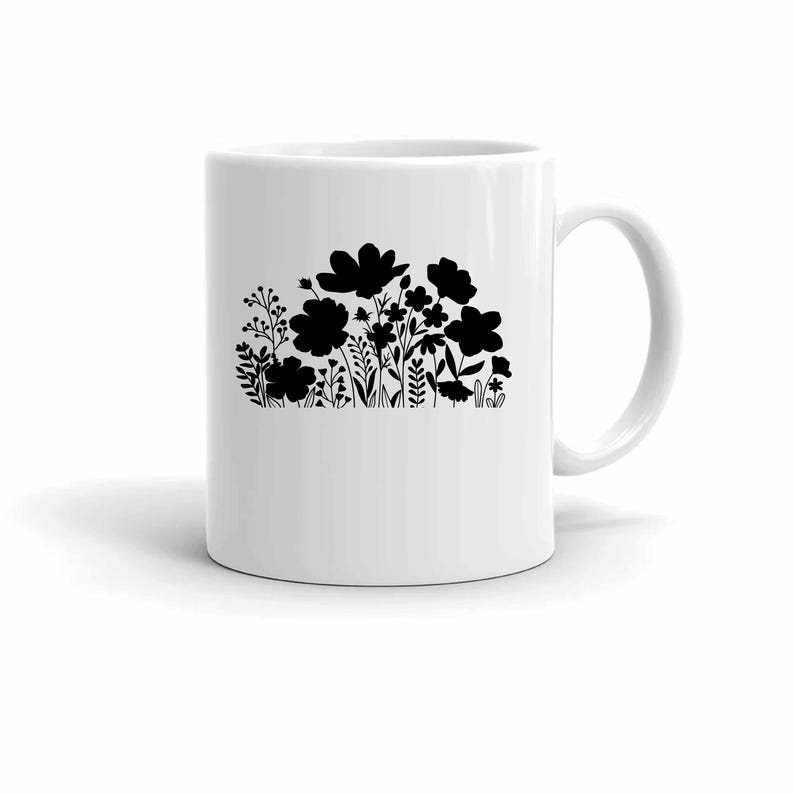 May include: White ceramic mug with a black floral design. The design features various flower and plant silhouettes. The mug has a curved handle and a smooth, glossy finish. Ideal for tea, coffee, or any drink.