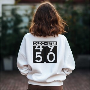 May include: White sweatshirt with black text that reads "Oldometer 49 50".