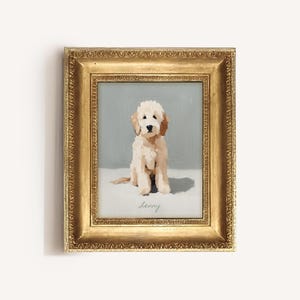 Peut inclure: Peinture encadrée d'un chiot clair aux oreilles tombantes, assis sur une surface blanche sur fond bleu clair. La peinture est dans un cadre doré orné, et le nom du chiot, "Lenny", est écrit en cursive.