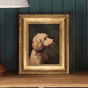 Op de afbeelding: Een ingelijst olieverfschilderij van een lichtbruine hond met zijn hoofd naar rechts gedraaid. De hond is geplaatst tegen een donkergroene achtergrond. De lijst is goudkleurig met een decoratieve rand.