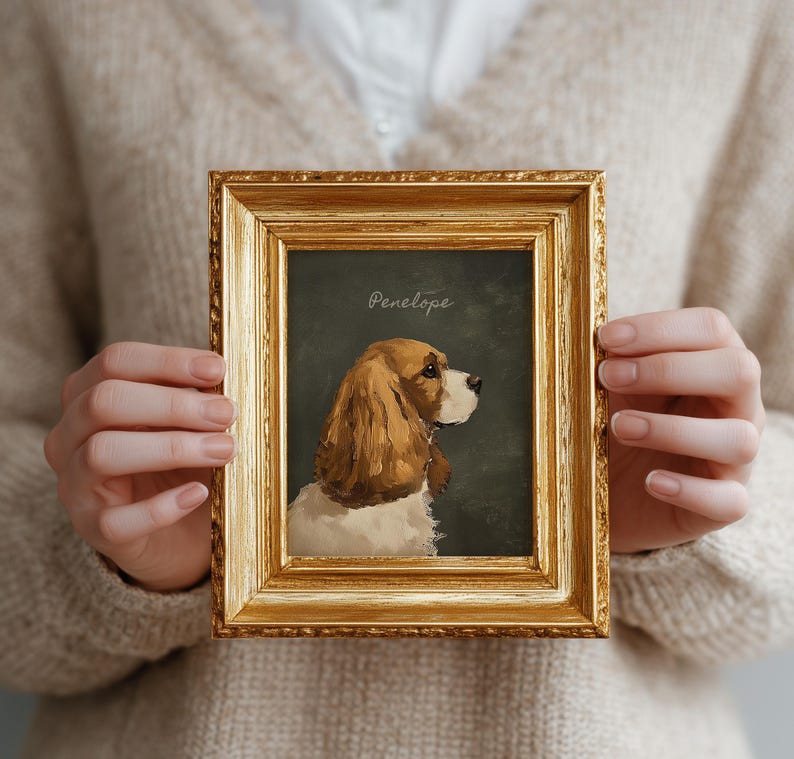 May include: A framed portrait of a dog, featuring a golden ornate frame. The artwork depicts a Cocker Spaniel with brown and white fur, set against a dark green background. The name "Penelope" is written in cursive at the top.