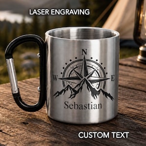 Può includere: Tazza da campeggio in acciaio inossidabile con manico nero e design a bussola inciso. Il design della bussola include una catena montuosa e il nome "Sebastian". La tazza presenta le scritte "LASER ENGRAVING" e "CUSTOM TEXT".