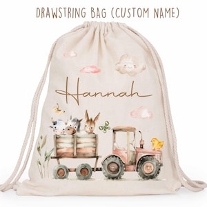 Puede incluir: Una bolsa con cordón beige con una ilustración de acuarela de un tractor que transporta animales de granja. El nombre "Hannah" está escrito en cursiva. La bolsa también presenta el texto "DRAWSTRING BAG (CUSTOM NAME)".