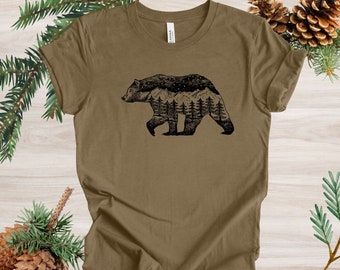 Può includere: Una maglietta marrone con una silhouette nera di un orso con una catena montuosa e alberi all'interno del corpo dell'orso.