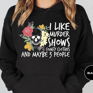 a woman wearing a black hoodie that says i like murder shows and maybe 3