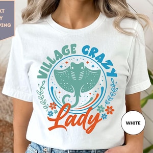 a woman wearing a white t - shirt with the words village crazy lady on it