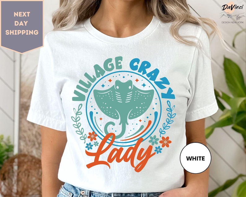 a woman wearing a white t - shirt with the words village crazy lady on it