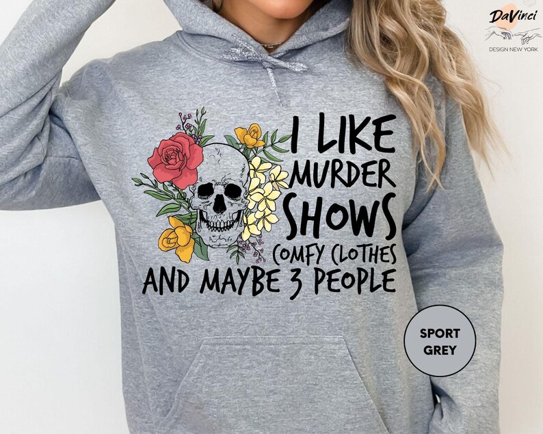 a woman wearing a grey hoodie with a skull and flowers on it