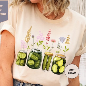 a woman wearing a t - shirt with pickles in jars