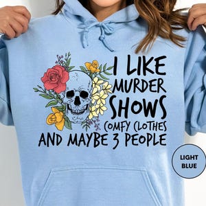 a woman wearing a blue hoodie that says i like murder shows and maybe 3