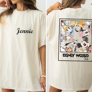 A woman wearing a white t-shirt with a Disney World-themed design on the back.