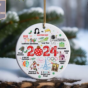 May include: A white round Christmas ornament with a red and white polka dot ornament in the center. The ornament has the year 2024 in red and white text. The ornament is surrounded by various illustrations of events that happened in 2024, including a cicada invasion, a ball of confusion, women's basketball, weight-less drugs, a billionaire on a space walk, inflation, and a leap year.