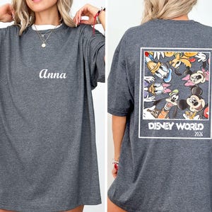 a woman wearing a gray t-shirt with a Disney World logo and text on the back.