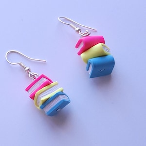 May include: A pair of silver dangle earrings with a stack of three colorful polymer clay books. The books are pink, yellow, and blue.