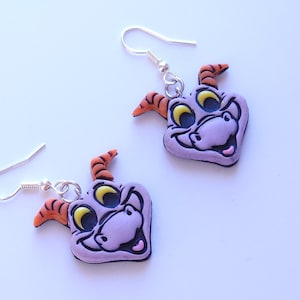 May include: Purple dragon head dangle earrings with orange horns and yellow eyes. The earrings are made of polymer clay and have silver hooks.
