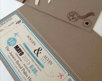 May include: A blue and white wedding invitation in the shape of a boarding pass with a plane icon. The invitation reads "Soojin & Alvin Invite" and includes the date "May 18, 2013" and the time "6:30pm". The invitation also includes the location "The James Royal Palm Hotel" and the address "1545 Collins Ave | Miami Beach, FL. | 33139".
