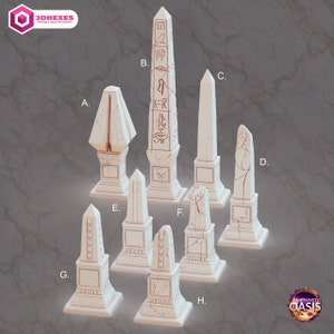 May include: Eight white, detailed, miniature stone obelisks with various carvings and designs. The obelisks are arranged in a semi-circle on a gray background. The text "3DHEXES" and "AMETHYST OASIS" are visible in the image.