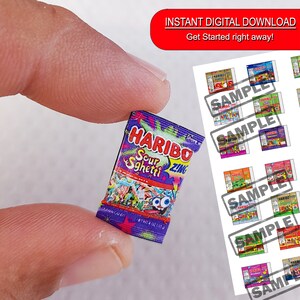 May include: A miniature package of Haribo Sour Sgheti Zing gummy candies. The package is purple and features a cartoon image of gummy worms. The text on the package reads "Haribo Sour Sgheti Zing".