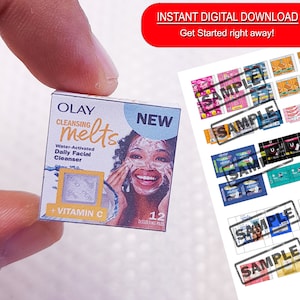 May include: A miniature box of Olay Cleansing Melts with Vitamin C. The box is white with a pink and yellow design. It features a woman with a smiling face and the text "NEW" in large letters. The box says "12 Dissolving Pads".