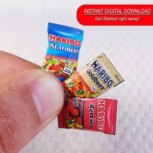 May include: Three miniature packages of Haribo gummy candies. The packages are red, blue, and gold with the Haribo logo and the flavors "Starmix", "Goldbears", and "Berries".