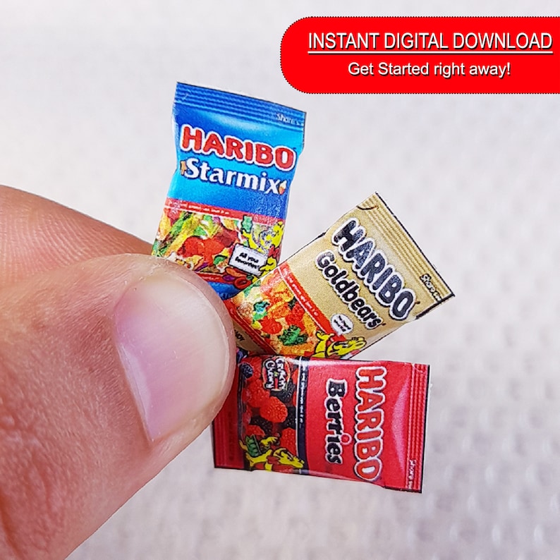 May include: Three miniature packages of Haribo gummy candies. The packages are red, blue, and gold with the Haribo logo and the flavors "Starmix", "Goldbears", and "Berries".