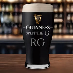 Op de afbeelding: Een pint Guinness stout in een hoog glas, met een romige witte schuimkraag. Het glas heeft het Guinness-logo, een gouden harp, en de tekst "-Guinness- Split the G RG" in het wit.