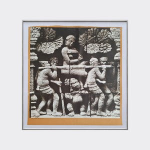 Peut inclure: Une impression encadrée en noir et blanc représentant une sculpture en relief en pierre. La scène montre un personnage central assis sur une litière portée par quatre individus, avec des motifs de feuilles de lotus en arrière-plan.