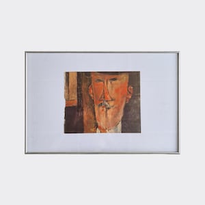 May include: A framed print of a painting featuring a man with a hat and a mustache. The artwork has a distinctive style with bold lines and a muted color palette, dominated by shades of orange, brown, and black. The frame is silver.