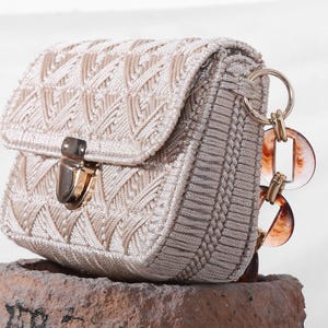 May include: A beige woven handbag with a gold clasp and a brown plastic chain strap.