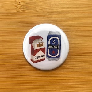 Może przedstawiać: Biały guzik z ilustracjami paczki papierosów i puszki alkoholu. Paczka papierosów jest czerwono-biała ze słowem "Cigarettes". Puszka ma napisy "& ALCOHOL".