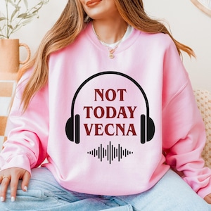 May include: Pink sweatshirt with the text "NOT TODAY VECNA" in maroon, framed by a black headphone design. Below the text is a black sound wave graphic. The sweatshirt is a solid pink color.