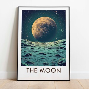 Puede incluir: Impresión artística enmarcada que muestra una luna texturizada sobre un cielo estrellado. La luna está sobre un paisaje con agua y rocas. El texto "THE MOON" está en la parte inferior de la impresión.