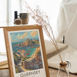 May include: A framed print of a colorful illustration of a coastal scene in Guernsey, Channel Islands. The print features a small house, a rocky coastline, and a blue ocean. The text "GUERNSEY Channel Islands" is printed at the bottom of the print.