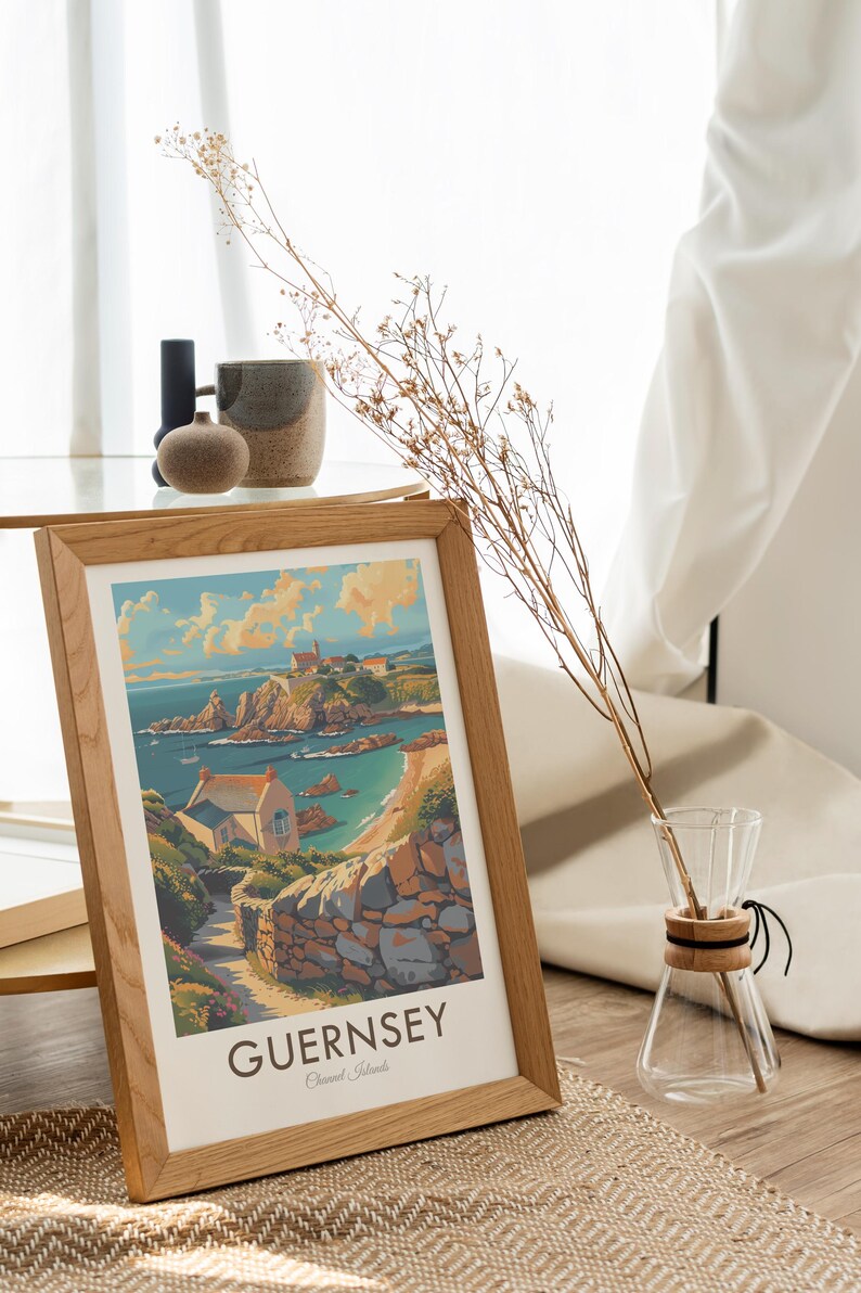 May include: A framed print of a colorful illustration of a coastal scene in Guernsey, Channel Islands. The print features a small house, a rocky coastline, and a blue ocean. The text "GUERNSEY Channel Islands" is printed at the bottom of the print.