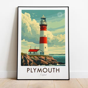 Puede incluir: Un póster enmarcado con un faro en Plymouth, Inglaterra. El faro es blanco con una franja roja, sobre un cielo azul con nubes. El póster incluye el texto "PLYMOUTH England".