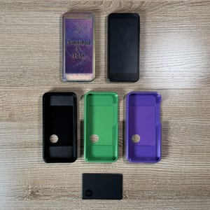 Könnte beinhalten: Ein Set mit sechs Handyhüllen, darunter eine schwarze Hülle mit einem Loch, eine grüne Hülle, eine violette Hülle, eine schwarze Hülle mit einem Logo und zwei Handybildschirme. Ein Bildschirm zeigt den Text "OmniPod 5 PDM".
