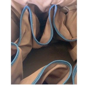 Può includere: L'interno di una borsa di tela marrone con più tasche in tessuto blu.